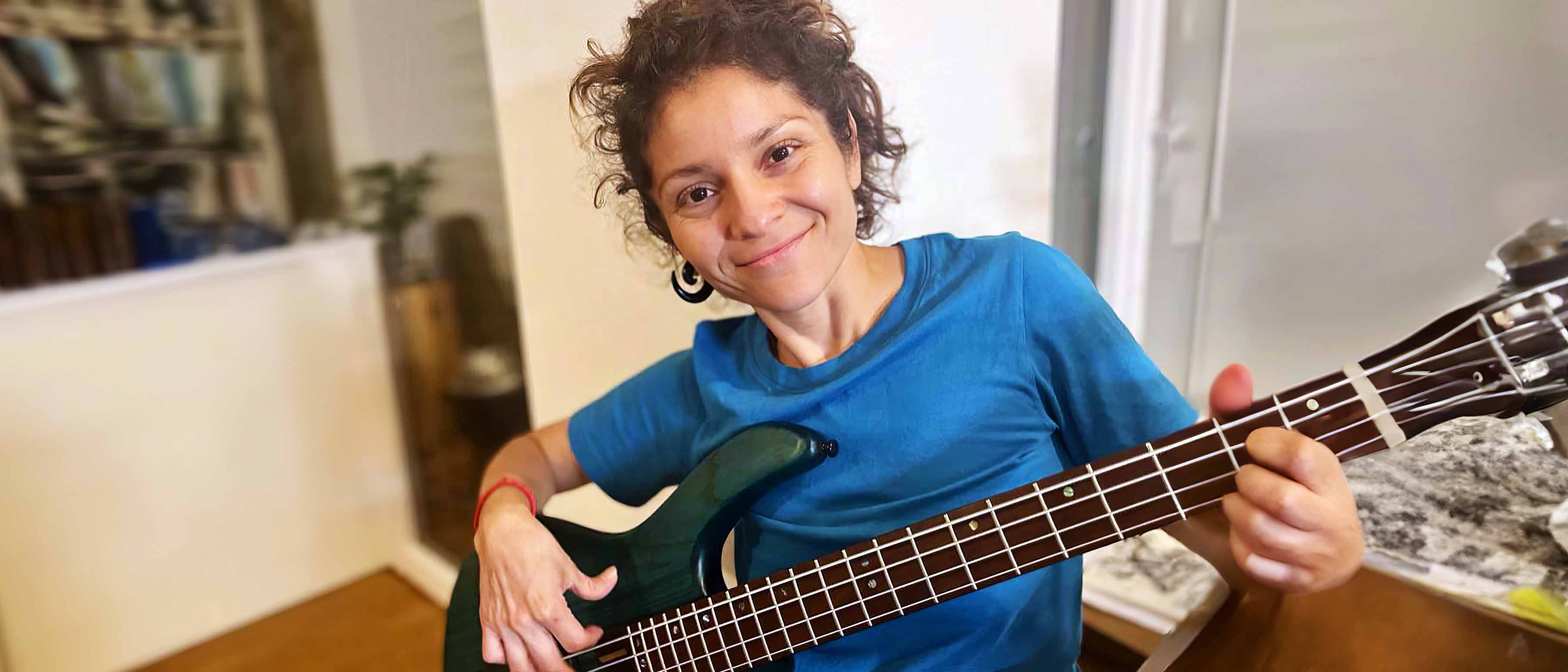 Maria Moctezuma sonriente tocando el bajo en casa.